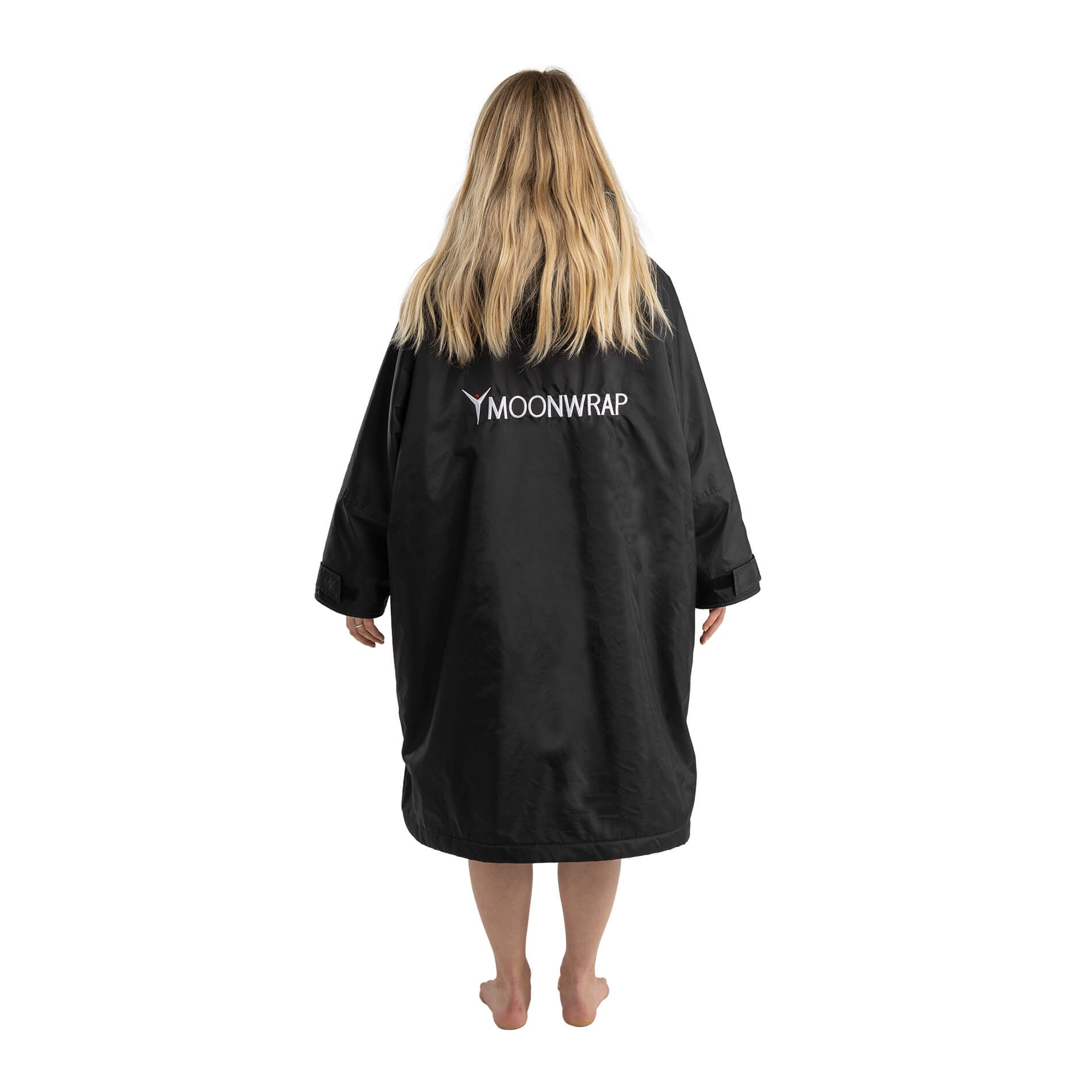 The back of a Woman wearing the Full length photo of a Woman in the Black Frostfire Moonwrap Waterproof Changing Robe for Cold Water Swimming.