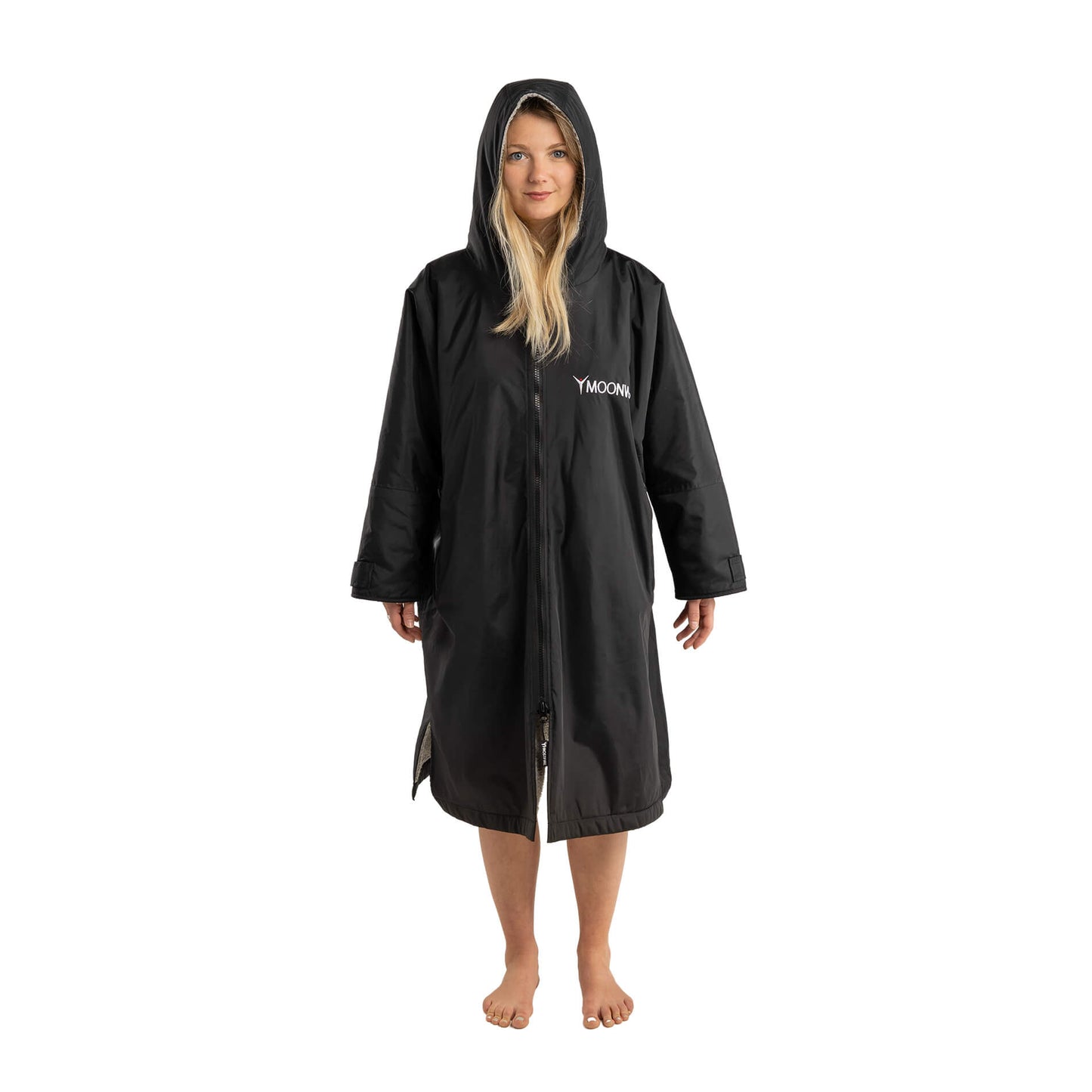 Full length photo of a Woman in the Black Frostfire Moonwrap Waterproof Changing Robe for Open Water Swimmers. The Woman has the hood up.