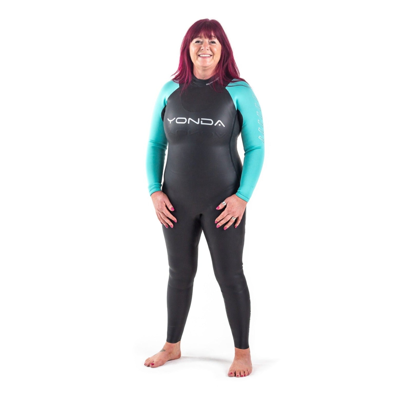 Front view of a women in a Spook Wetsuit by Yonda. A beginners Wild Swimming Wetsuit. It is black with aqua arms and the lady is smiling.