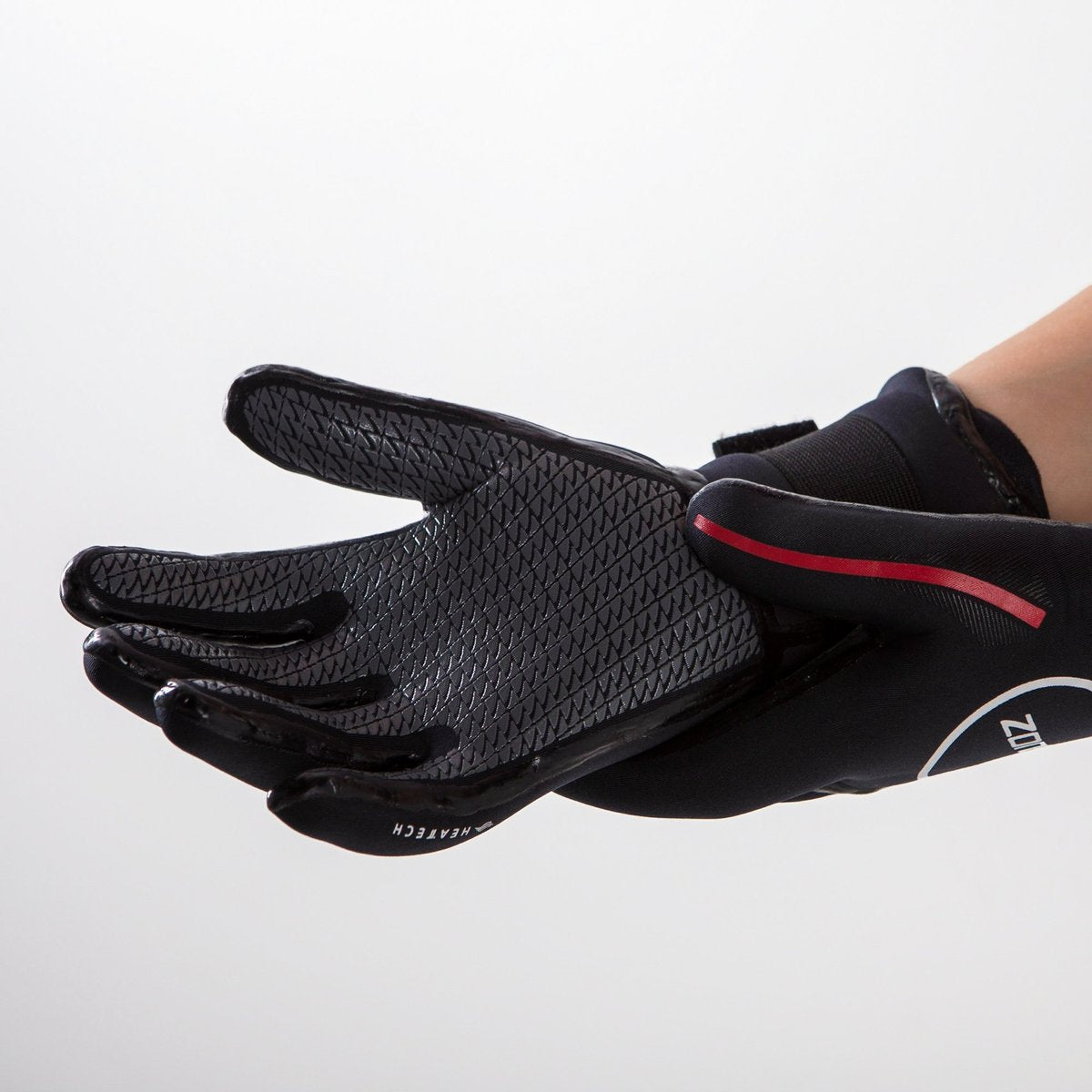 A close up photo of a persons hand wearing the Zone 3 Heat Tech Warmth Neoprene Gloves for Open Water Swimming. Their right hand is palm up showing the grips on the gloves: