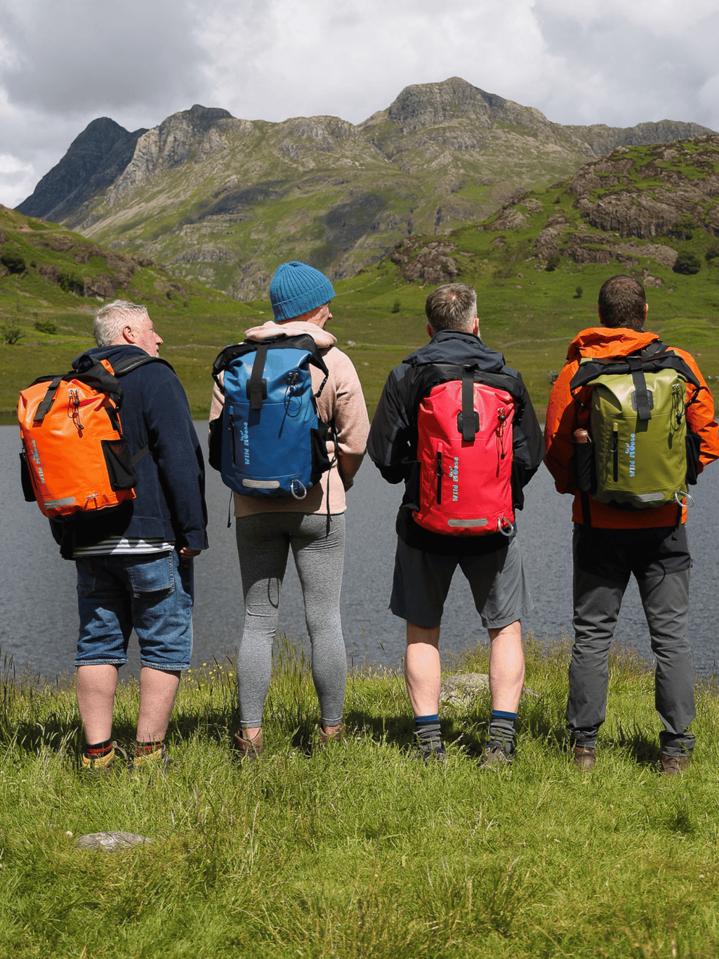 Wild Swimmers Wearing bright coloured Waterproof Backpacks against some mountains ideal for Wild Swim Kit Bags.