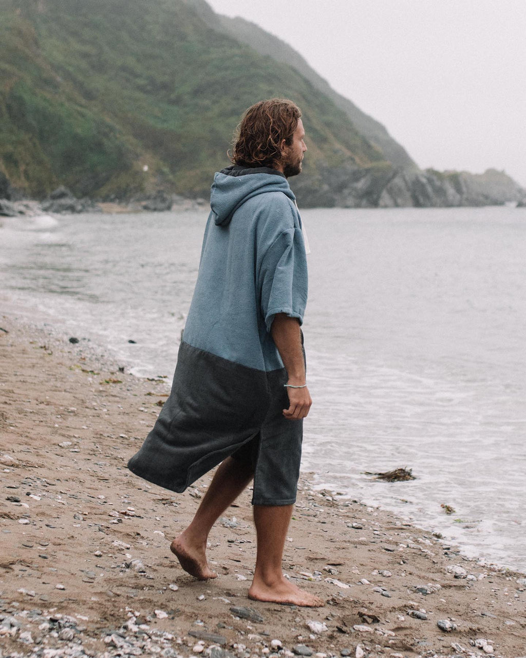 Lead_men2 - Man wears a Vivida Original Poncho Towel Changing Robe - Mineral Blue / Anthracite Grey