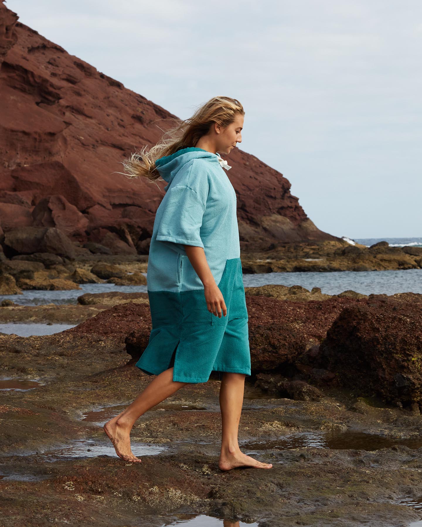 Lead_women2 - Woman wears a Vivida Original Adult Poncho Towel Changing Robe - Turquoise Teal / Pacific Teal. Sticker reads Women's Health Best Towelling Changing Robe