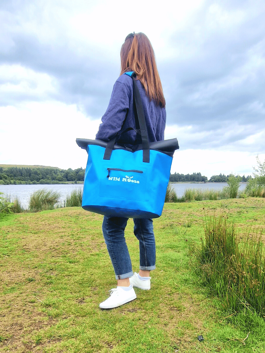 A Woman with a bright Blue Waterproof Bag over her shoulder - ideal for Swim Kit Bag.