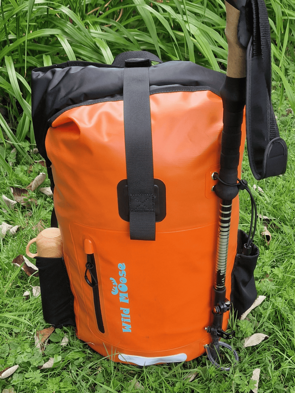 Wild moose Bright orange waterproof backpack for open water swimming, placed on grass.
