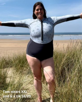 Woman wearing a Long Sleeve Swimsuit - Vivida Lifestyle XX large - XXL -  Cold water Swimming Swimsuit Thermal Neoprene - stood in the sand dunes on a  beach with her arms spread out
