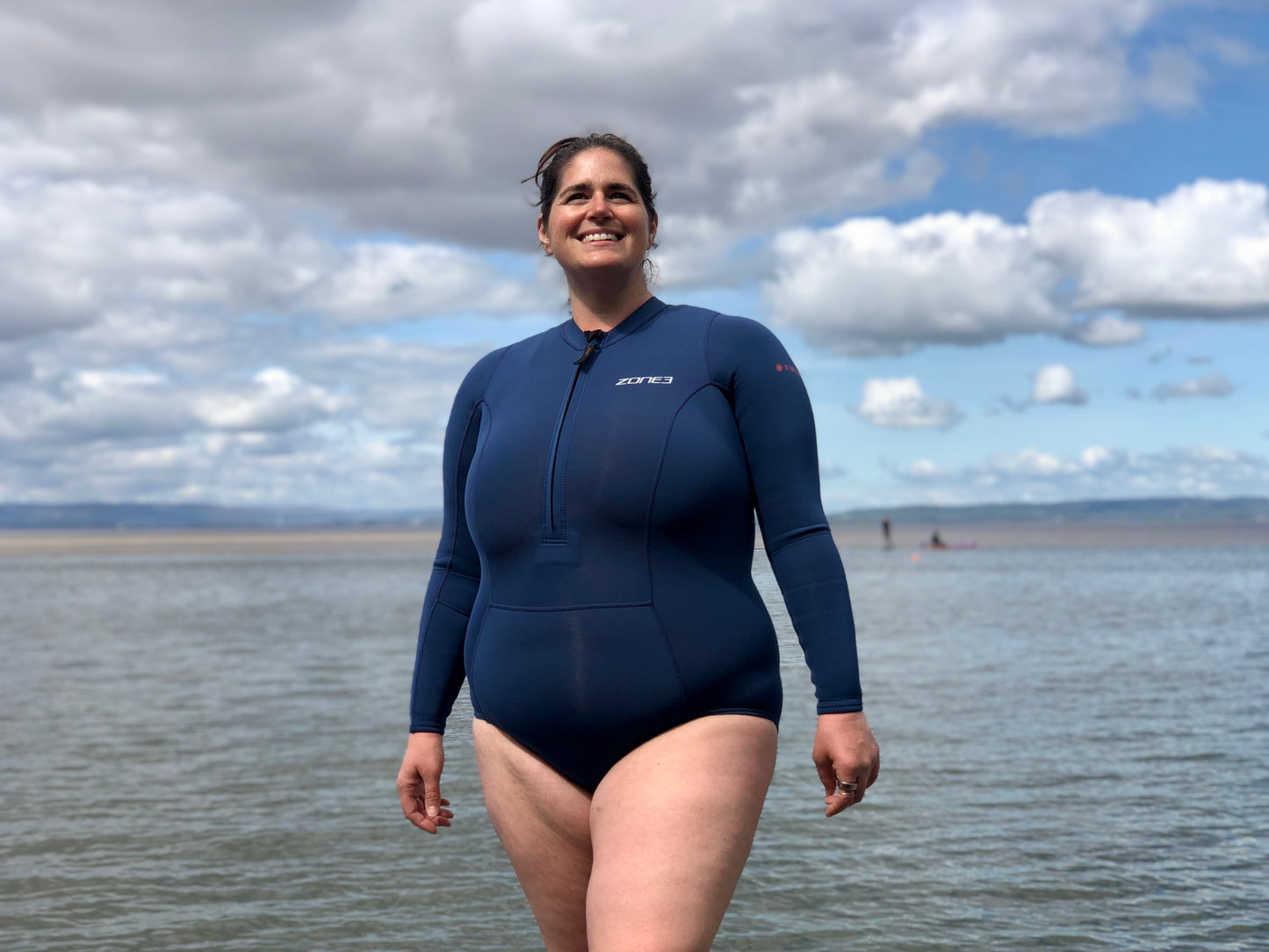 A plus size Swimmer by a lake after a cold water swim wearing the Zone 3 Women's Yulex Long sleeve Swimsuit in XL size.