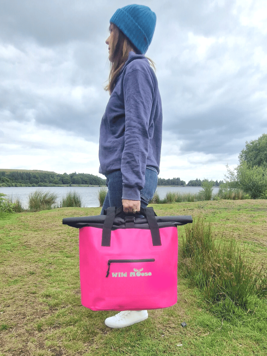 A Woman Holding a bright Pink Waterproof Bag - ideal Swim Kit Bag for Wild Swimmers.