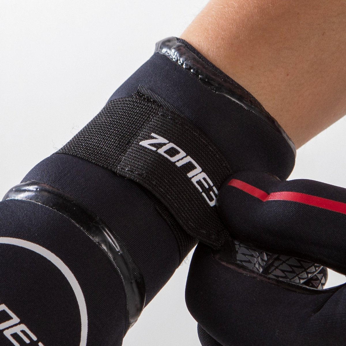 Close up of the wrist of the Zone 3 Heat Tech Warmth Neoprene Gloves for Cold Water Swimming. The Velcro wrist strap is in the shot showing the persons hand securing the Velcro strip.